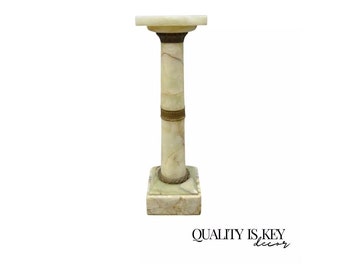 May include: A white marble pedestal with a gold trim. The pedestal is a column with a square base and a square top.