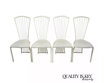 May include: Four white dining chairs with a fan-shaped back and a white padded seat. The chairs are made of metal and have a simple, modern design.