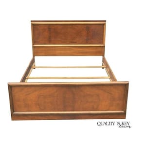 May include: A wooden bed frame with a headboard and footboard. The frame is made of a dark brown wood with a natural grain pattern. The headboard and footboard have a rectangular design. The bed frame is empty, with wooden slats visible.