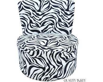 May include: A small, upholstered chair with a zebra print pattern in black and white. The chair has a rounded seat and a small backrest. The text "QUALITY IS KEY decor" is printed in black at the bottom right.