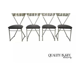 May include: Set of four silver metal chairs with gray fabric seats. The chairs have a unique X-shaped design and a slightly curved back.