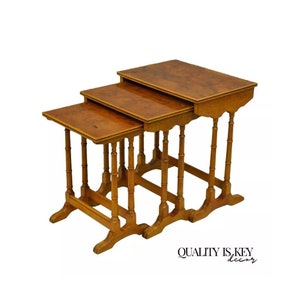 May include: Set of three nesting tables with a wood grain finish. The tables have a rectangular top and a simple, elegant design with turned legs.