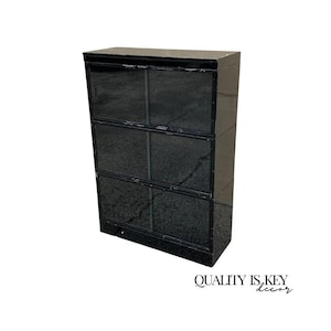 May include: A black cabinet with six compartments. The cabinet has a glossy finish and a rectangular shape. The text "QUALITY IS KEY decor" is at the bottom right corner.