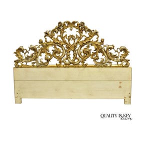 May include: Ornate headboard with a cream-colored base and a detailed gold-colored, scrollwork design. The headboard features a rectangular base with a decorative top, perfect for a bedroom. The design includes floral and swirling patterns.