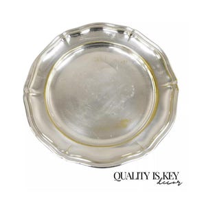 Puede incluir: Un plato de servicio plateado con un borde festoneado. El plato es redondo y tiene un acabado brillante.