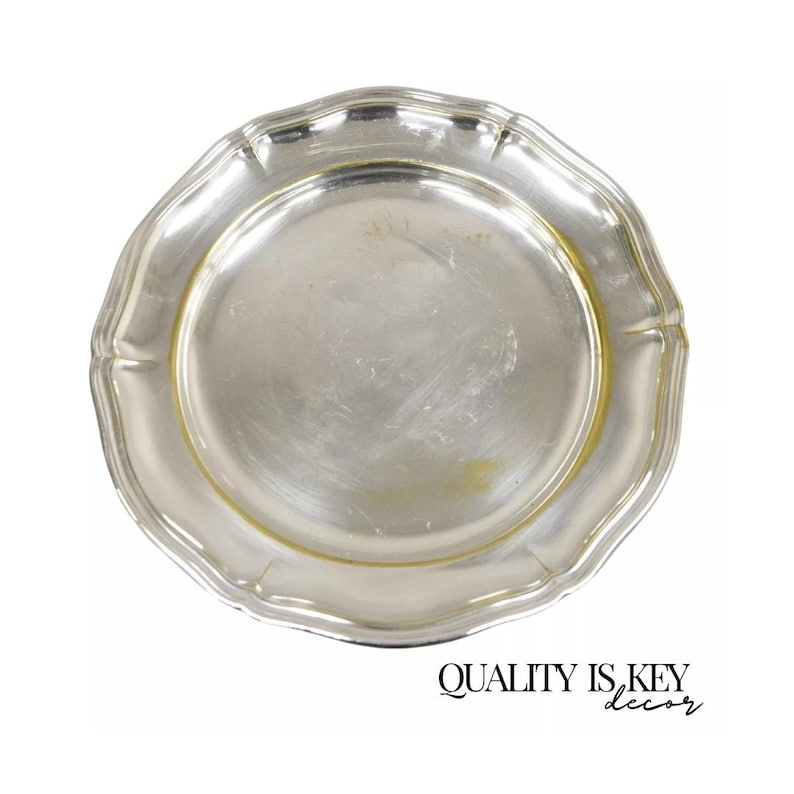 Puede incluir: Un plato de servicio plateado con un borde festoneado. El plato es redondo y tiene un acabado brillante.