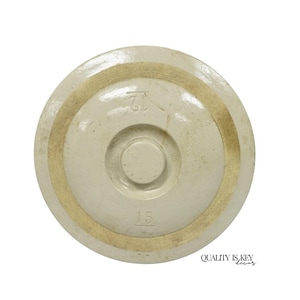 May include: A circular, off-white ceramic lid with a smooth, glazed finish. The top surface features a central circular knob, a raised ring detail, and the stamped number 12. The underside has a circular indentation and the number 15 stamped.