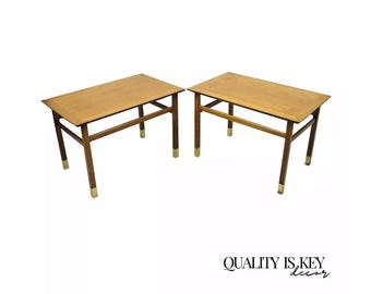 May include: A pair of mid-century modern end tables with a wood top and brass accents. The tables have a simple, geometric design and are in good condition.