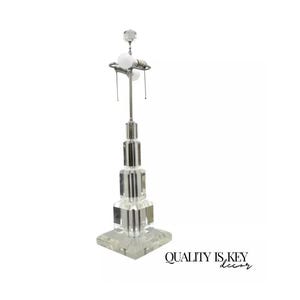 May include: A crystal table lamp with a geometric design. The lamp has a clear glass base and a silver metal shade. The lamp is turned on and the light is shining through the crystal.