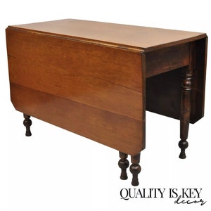 May include: A vintage wooden drop leaf table with turned legs. The table is made of solid wood and has a rich brown finish. The table is in good condition and has a few minor scratches and marks.