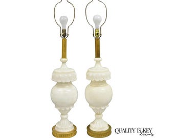 May include: Pair of ivory-colored table lamps with a classic design. Each lamp features a bulb, brass accents, and a decorative base. The lamps have a height of approximately 30 inches.