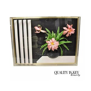 May include: A framed 3D wall art piece featuring pink flowers and green leaves in a black vase against a black and white striped background.
