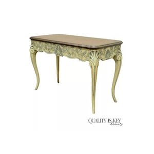 May include: A light yellow console table with a carved floral design on the front edge. The table has a brown top and four legs with a curved design.