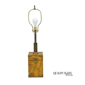May include: A vintage table lamp with a wooden base and brass accents. The base is a square box with a decorative lock and corner brackets. The lamp has a brass stem and a curved arm holding a lightbulb. The lamp is a warm, inviting piece of home decor.