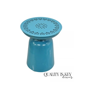 May include: A teal blue side table with a round top featuring a cut-out design. The table has a wide base and a narrow top.