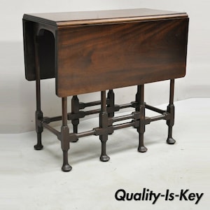 May include: A dark brown wooden folding table with a unique, intricate metal base. The table has a rectangular top and a sturdy, open-frame base with multiple crossbars.