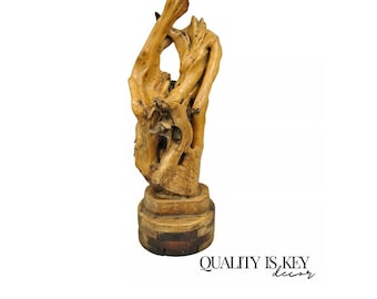May include: A wooden sculpture of a twisted tree branch with a natural wood finish. The sculpture is mounted on a wooden base.