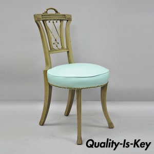 May include: A light blue upholstered chair with a wooden frame and a decorative back. The chair has a simple design with a rounded seat and four legs.