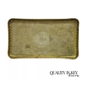 May include: A large, rectangular brass tray with a scalloped edge. The tray has a slightly worn, antique finish and a raised oval design in the center.