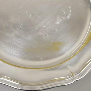 Puede incluir: Una fuente de servir de plata con un borde festoneado y un borde dorado.