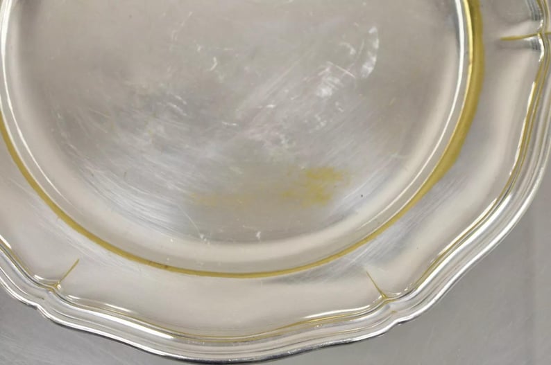 Puede incluir: Una fuente de servir de plata con un borde festoneado y un borde dorado.