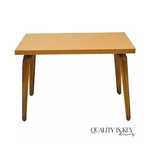 May include: A light brown wooden coffee table with a rectangular top and four legs. The legs are curved and have a light brown finish.
