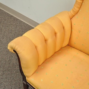 May include: A yellow armchair with a tufted back and a patterned fabric. The chair has a wooden frame and a high back.