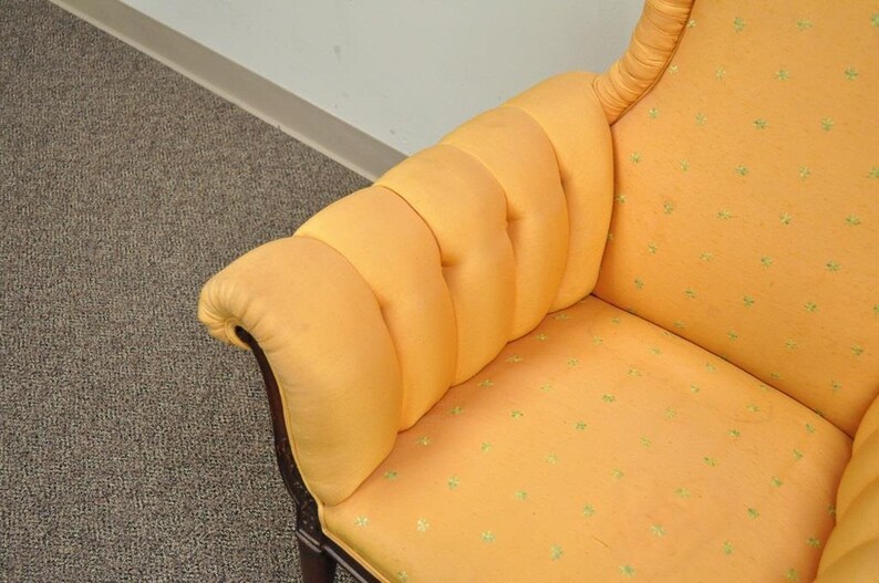 May include: A yellow armchair with a tufted back and a patterned fabric. The chair has a wooden frame and a high back.