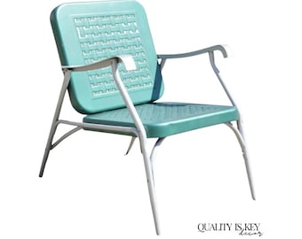 May include: A vintage teal metal chair with a white frame. The chair has a woven pattern on the back and seat, with armrests. The chair is designed for outdoor use. The text "QUALITY IS KEY decor" is in the bottom right corner.