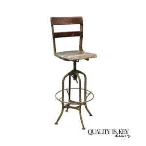 May include: An antique industrial-style adjustable height stool. It features a distressed wooden seat and backrest, supported by a metal frame with a footrest ring. The metal has a weathered, aged appearance. The stool is designed for functionality and vintage aesthetic.