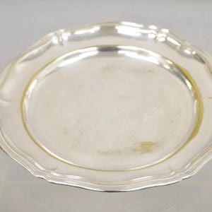 Puede incluir: Un plato de servir de plata con un borde festoneado.