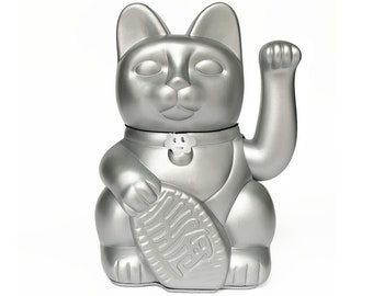 May include: A silver lucky cat figurine with a raised paw, holding a coin with Chinese characters. The cat has a black collar with a small flower charm.