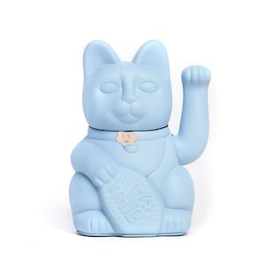 May include: A light blue Maneki Neko figurine with a raised paw, holding a fish. The cat has a collar with a small charm. The figurine is a solid color and sits on a white background.