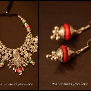 May include: A silver necklace with red and green beads and a silver pendant. The necklace is on a brown surface. Two silver earrings with red beads are also shown.