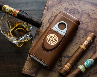 May include: A brown leather cigar case with a silver cigar cutter and a gold monogram "AS". The case is open and the cutter is visible. There are three cigars on a map background.