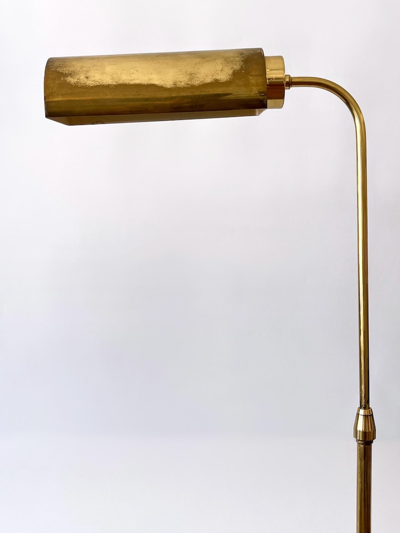 Puede incluir: Una l&aacute;mpara de pie vintage de lat&oacute;n con una pantalla rectangular y un brazo curvo. La l&aacute;mpara tiene un tono dorado c&aacute;lido y un dise&ntilde;o cl&aacute;sico. La altura de la l&aacute;mpara es de aproximadamente 152 cm.
