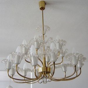 May include: A gold chandelier with clear glass shades and crystal accents. The chandelier has multiple arms and is hanging from the ceiling.