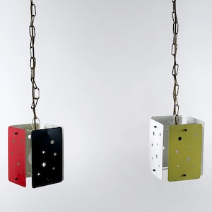 Op de afbeelding: Twee hangende pendellampen met een retro-ontwerp. Eén lamp heeft rode, zwarte en witte panelen, terwijl de andere witte, groene en gele panelen heeft. Elke lamp wordt opgehangen aan een bruine ketting.