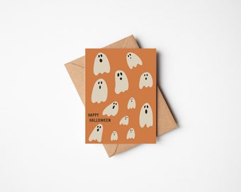 May include: A Halloween greeting card with a burnt orange background featuring multiple white ghost illustrations. The words "Happy Halloween" are printed in black. The card is paired with a brown envelope.