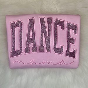 May include: Pink sweatshirt with the word "DANCE" in sparkly pink letters and the word "mama" underneath.