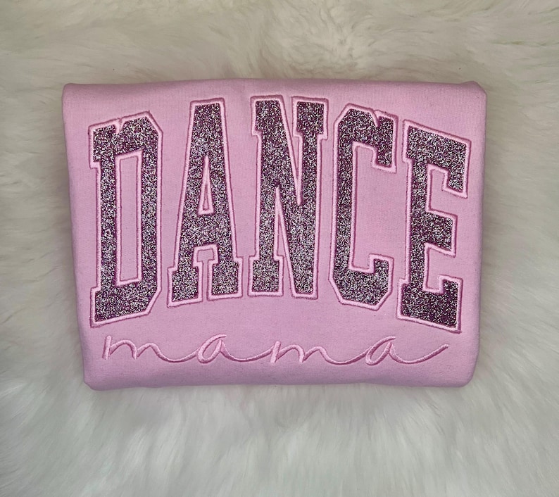 May include: Pink sweatshirt with the word "DANCE" in sparkly pink letters and the word "mama" underneath.