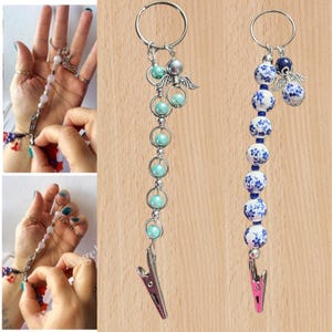 May include: Two beaded keychains. One has turquoise beads and silver details, including a small angel charm. The other has white and blue floral beads with a pink clip. Both have a metal clip and a keyring.