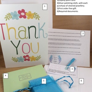 May include: A thank you card with a floral design and the text "Thank You". The card is surrounded by a variety of items included in a package, such as a silver polishing cloth, a handwritten note, a loyalty card, and a small blue bag.
