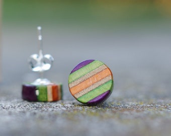 May include: A pair of round, colorful earrings made from recycled skateboard wood. The earrings have a purple, green, and orange striped pattern.