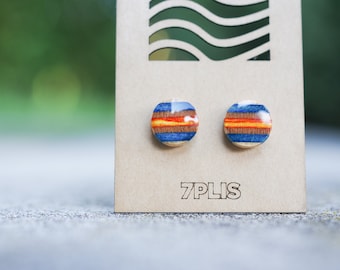 May include: A pair of round, blue and orange striped earrings made from recycled skateboard wood. The earrings are displayed on a brown card with the text "7PLIS".