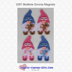 May include: Four plastic canvas gnome magnets, two blue and two pink. Each gnome is holding a stuffed animal. The gnomes are wearing glasses and have a white beard. The text "Plastic-Canvas-Kits.Com" is at the bottom of the image.