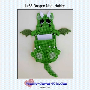 May include: Green plastic canvas dragon note holder with white eyes and horns. The dragon is holding a white note card in its front paws. The note holder is a craft project and is available as a pattern.