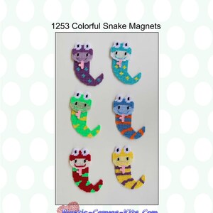 May include: A set of four colorful snake magnets. The snakes are made of plastic canvas and are decorated with different colors and patterns. The magnets are perfect for adding a touch of whimsy to any refrigerator or metal surface.