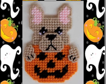 Puede incluir: Un patrón de lona de plástico para un bulldog francés que lleva un disfraz de calabaza. El patrón está en tonos de marrón, naranja, negro y rosa. El patrón se titula "Ildog in Pumpkin Magnet".