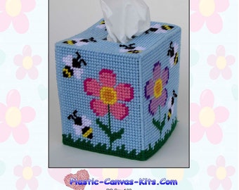 May include: A blue plastic canvas tissue box cover with a bee and flower design. The cover features pink, purple, yellow, and green flowers with bees flying around them. The text "Plastic-Canvas-Kits.Com" is printed on the bottom of the image.